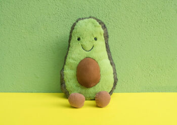 Toy avocado with yellow and green background