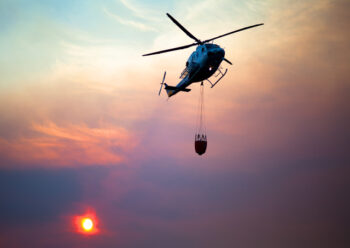 Helicopter in flight carrying large container of water