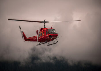 Red helicopter flying near low cloud