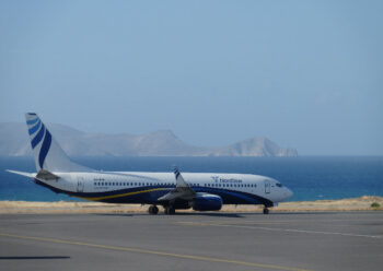 Plane taxiing at airport with sea and mountains in the background