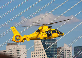 Yellow helicopter hovering above buildings