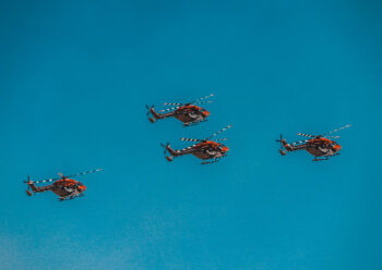 Four red helicopters flying in formation