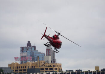 Red helicopter flying over buildings