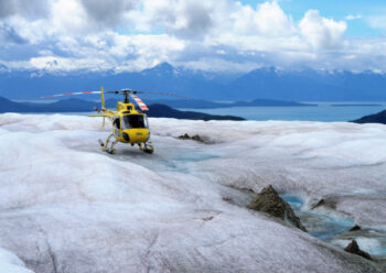 Yellow helicopter on snowy and icy rock