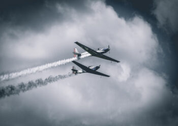 Two propeller planes flying in formation with smoke