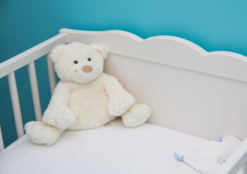 Teddy bear in the corner of a cot