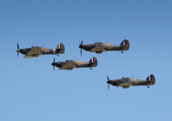 Four military propeller planes in flight