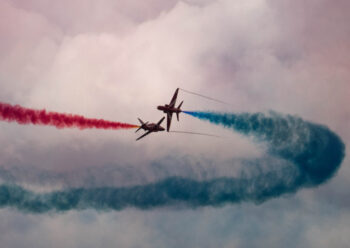 Red Arrows doing crossover manoeuvre with coloured smoke