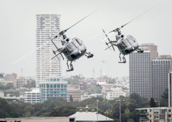 Two helicopters flying over a city